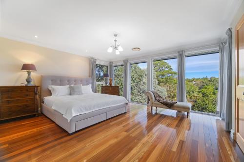 Schlafzimmer mit einem Bett, einem Stuhl und Fenstern in der Unterkunft House by the Harbor in Sydney