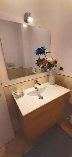 a bathroom sink with a mirror and a vase of flowers at Casa Mia Sirolo in Sirolo