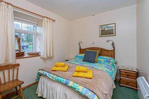 1 dormitorio con 1 cama con 2 almohadas amarillas en Ysgubor, en Tregarth