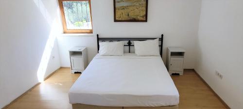 a bedroom with a white bed with two night stands at Muskebi Villa in Ortakent