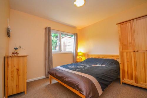 1 dormitorio con cama y ventana en Tan Dinas Lodge en Benllech