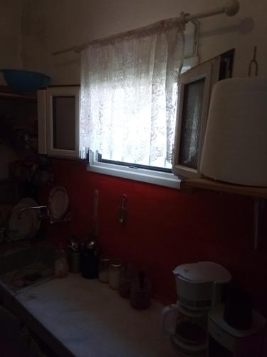 - une cuisine avec une fenêtre, un évier et un comptoir dans l'établissement Marathon agios panteleimon attiki Greece, à Panayía Mesosporítissa