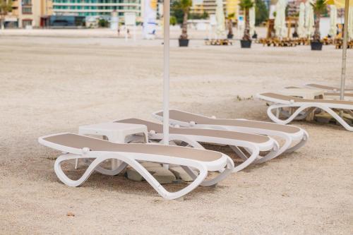 a row of white lounge chairs on a beach at Hotel Hawaii in Mamaia