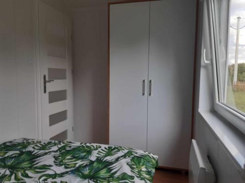 a bedroom with a bed and a cabinet and a window at Domek w Gruszkach in Gruszki