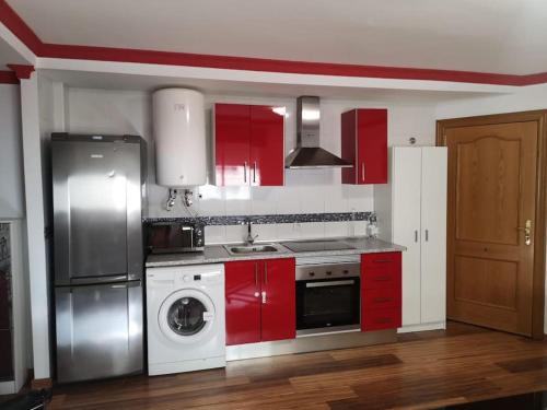 a kitchen with red cabinets and a washing machine at Apartamento Tropical by Bossh! Apartments in Salobreña