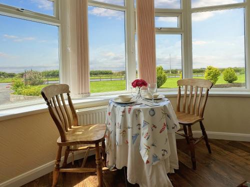 - une table avec deux chaises dans une chambre avec fenêtres dans l'établissement The Retreat @ Wolds View, à Bridlington