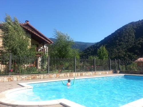 a person swimming in a swimming pool with mountains in the background at Posada El Hoyal in Pesaguero-La Parte