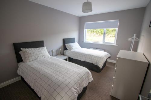 a bedroom with two beds and a window at Millbay View House in Kilkeel