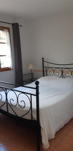 a bedroom with a black bed with white sheets and a window at La Pitchounette in La Colle-sur-Loup