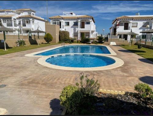 a swimming pool in front of a house at Family Apartment in Orihuela
