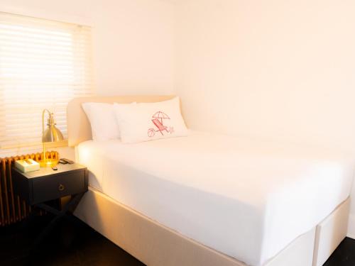a white bed with a bicycle pillow on it at Beachliner Hotel in Ocean Grove
