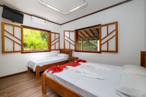 two beds in a room with two windows at Hotel Fazenda Colina dos Sonhos in Socorro