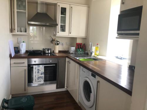 a kitchen with white cabinets and a washer at Amazing converted water tower! in Coulsdon