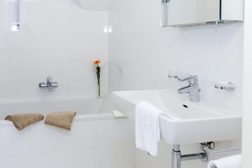 a white bathroom with a sink and a bath tub at Moor-Rosl Apartmenthotel in Gamlitz