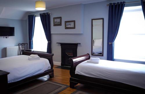 1 dormitorio con 2 camas, chimenea y espejo en Denvir's Coaching Inn en Downpatrick