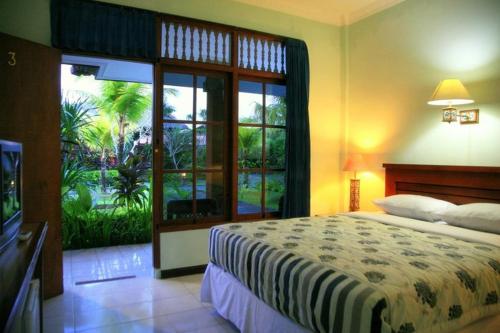a bedroom with a bed and a large window at D' Kubu Pratama Homestay in Nusa Dua