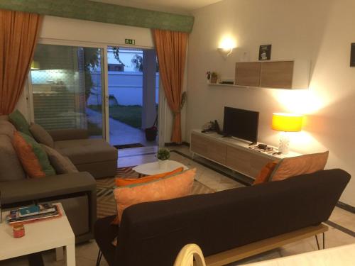 een woonkamer met een bank en een tv bij Apartamento perto da Praia Coelha in Albufeira