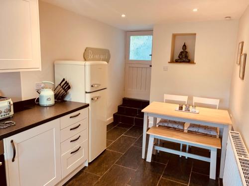 a kitchen with a white refrigerator and a table at The Beautiful Bobbin - Premium Cottage with views, local walks, wood burner & pubs in Tideswell