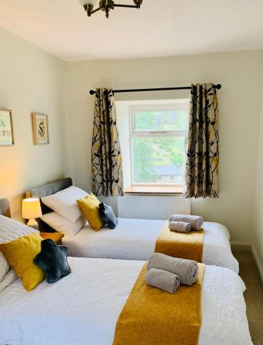 a bedroom with two beds and a window at The Beautiful Bobbin - Premium Cottage with views, local walks, wood burner & pubs in Tideswell