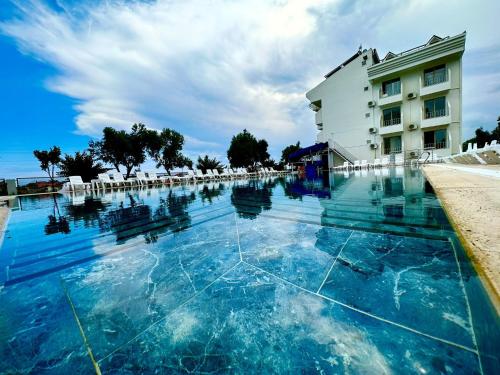 a swimming pool with blue water in front of a building at Colaklı Sunset Otel in Side