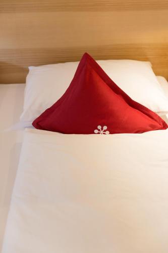 a red pillow sitting on top of a white bed at Familienhotel Mateera Gargellen / Montafon in Gargellen