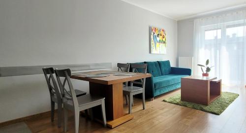 a living room with a table and a blue couch at Apartamenty MAGNOLIA in Namysłów