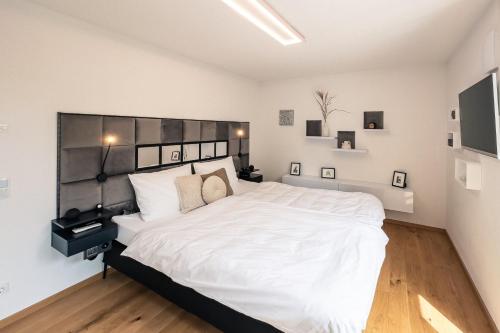 a bedroom with a large white bed with white walls at CREST - Alpdeluxe - Balkon-Wanne-Tiefgarage-BBQ in Kolbermoor