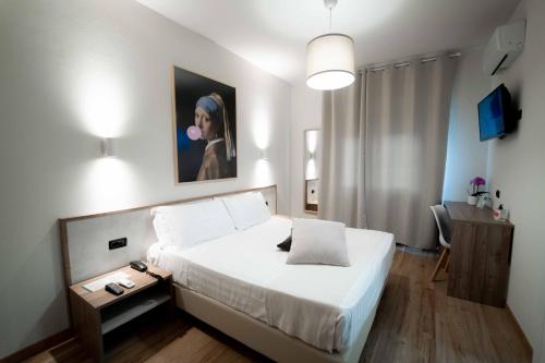 ein Schlafzimmer mit einem weißen Bett und einem Gemälde an der Wand in der Unterkunft EcoHotel Ristorante Milano in Borgo a Mozzano
