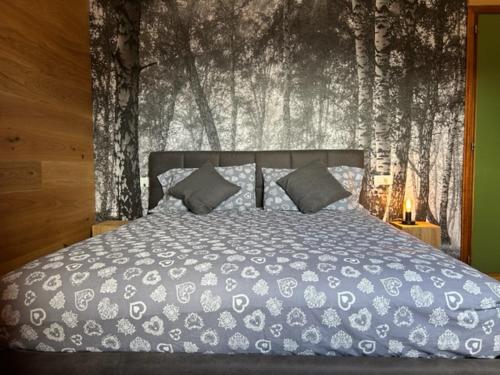a bed in a bedroom with a wall with trees at Perla Dolomiti Falt in Falcade