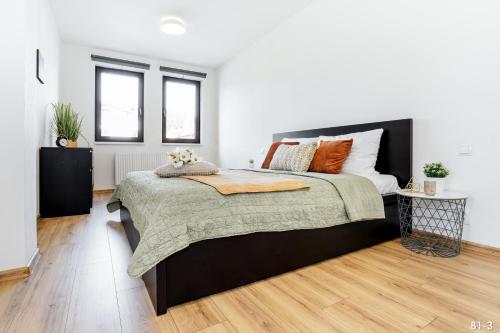 a bedroom with a large bed and two windows at KORZO Lipno in Lipno nad Vltavou