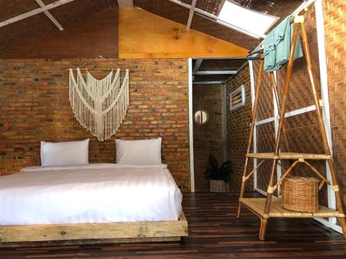 1 dormitorio con cama y pared de ladrillo en Hub Tata Guesthouse, en Tuk Tuk
