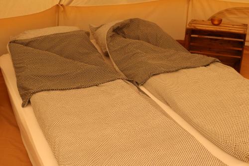 a bed is covered with a blanket at Haramara Tipi in Vester-Skerninge