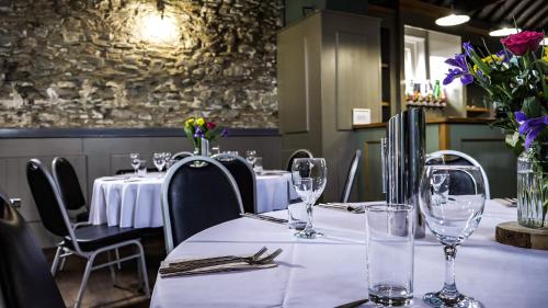 a table in a restaurant with white tables and chairs at Denvir's of Downpatrick in Downpatrick