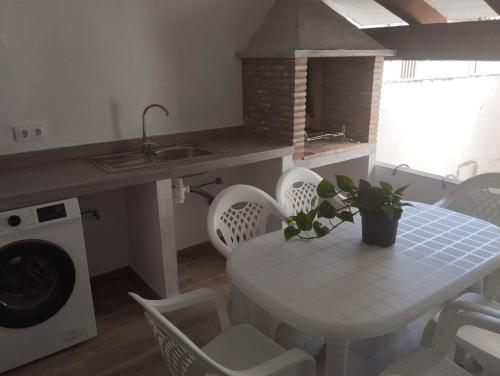 uma cozinha com uma mesa e cadeiras brancas e uma máquina de lavar roupa em CAN’SELMA 2 em Chella