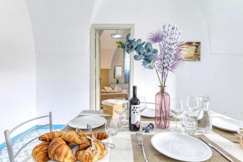 a table with plates of bread and a vase of flowers at Villa Cesarea Dimora di Charme in Santa Cesarea Terme