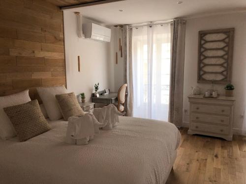 a bedroom with a bed with white sheets and a window at Le Cœur de la Bastide - Adult only in Carcassonne