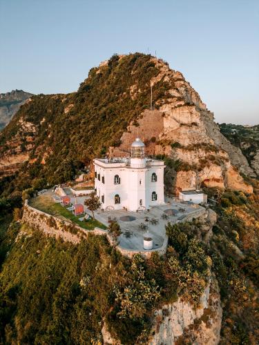 a white building on the side of a mountain at Faro Punta Imperatore in Ischia