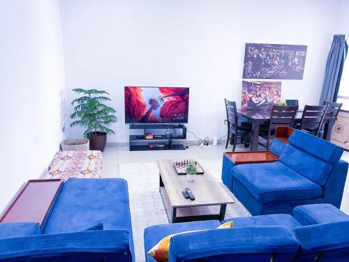 a living room with blue couches and a tv at Hawana Hostel in Dubai