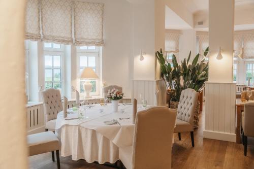 a dining room with a white table and chairs at Strandhotel Glücksburg in Glücksburg
