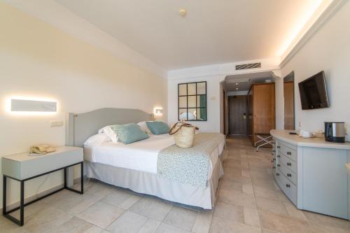 a bedroom with a bed and a desk and a television at CM Mallorca Palace - Only Adults in Sa Coma