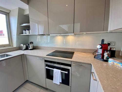 a kitchen with white cabinets and a stove top oven at Top floor luxury 3 bedroom near Baker St in London