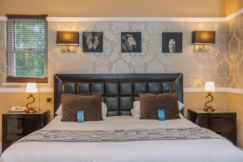 a bedroom with a large bed with two night stands at Muthu Belstead Brook Hotel in Ipswich