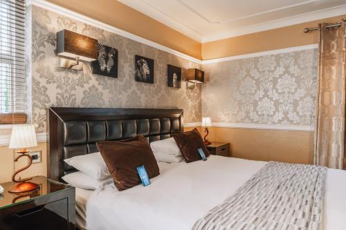 a bedroom with a large white bed with brown pillows at Muthu Belstead Brook Hotel in Ipswich