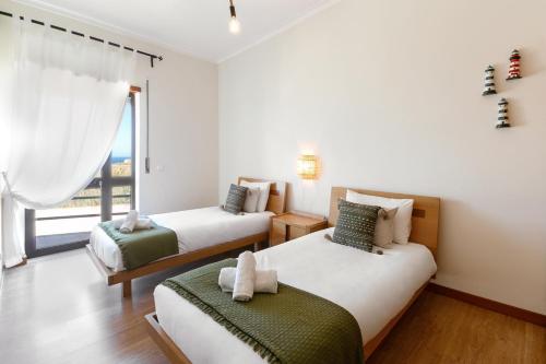 ein Schlafzimmer mit zwei Betten und einem Fenster in der Unterkunft Seaside Deluxe Flat in Peniche
