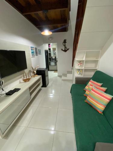 a living room with a green couch and a flat screen tv at Condomínio Village 4 Carneiros casa 40 in Tamandaré