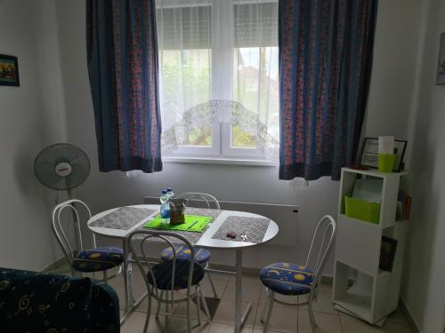a table and chairs in a room with a window at Zseki apartman in Hajdúszoboszló