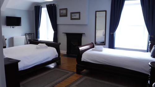 a room with two beds and a fireplace and two windows at Denvir's of Downpatrick in Downpatrick
