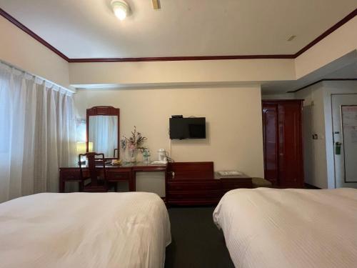 a hotel room with two beds and a desk at River Hotel in Chiayi City