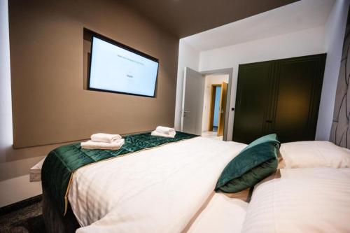 a bedroom with two beds and a tv on the wall at DMS Apartments & Suites Sarajevo in Vogošća