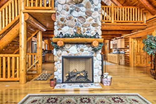 a living room with a stone fireplace in a log cabin at Spacious Twin Mountain Vacation Rental on 5 Acres! in Twin Mountain
